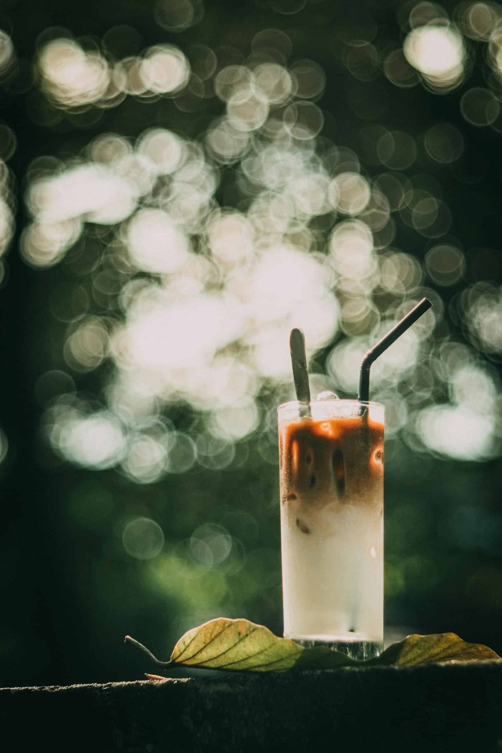 Chilled iced latte in sunlight with bokeh effect, perfect for summer coffee themes.